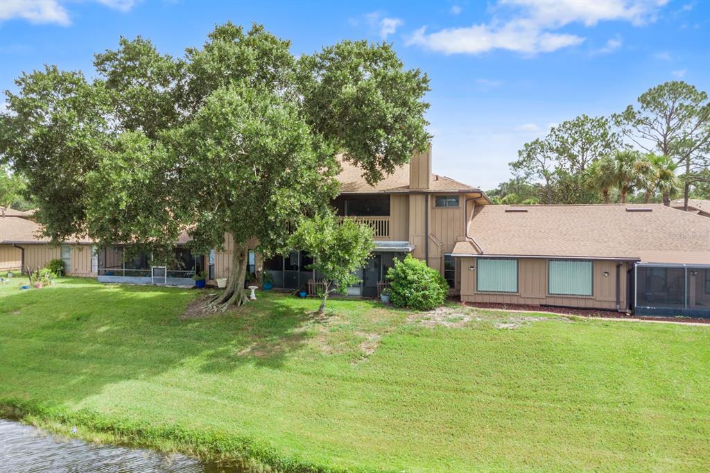 The exterior of a multi-story tan townhouse features a screened patio overlooking a grassy lawn — 182 HERON BAY CIRCLE, LAKE MARY, FL