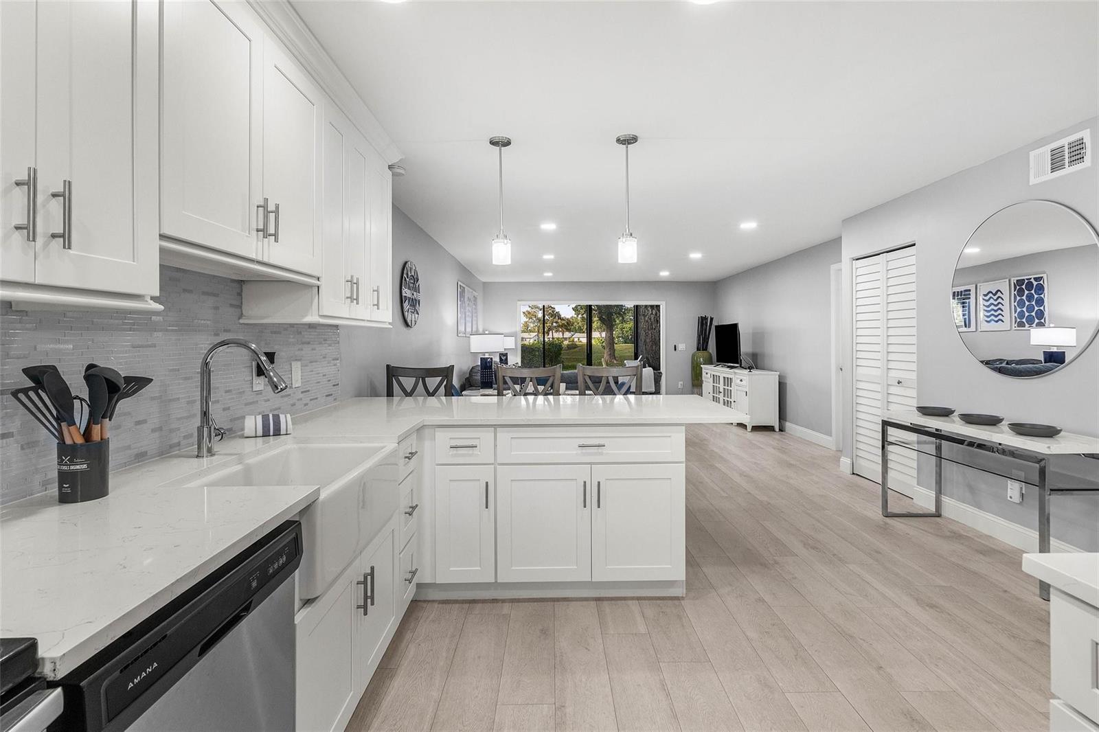 A modern white kitchen with quartz countertops and light wood floors opens to a living area — 9286 Vista Del Lago, Boca Raton FL 33428, BOCA RATON, FL