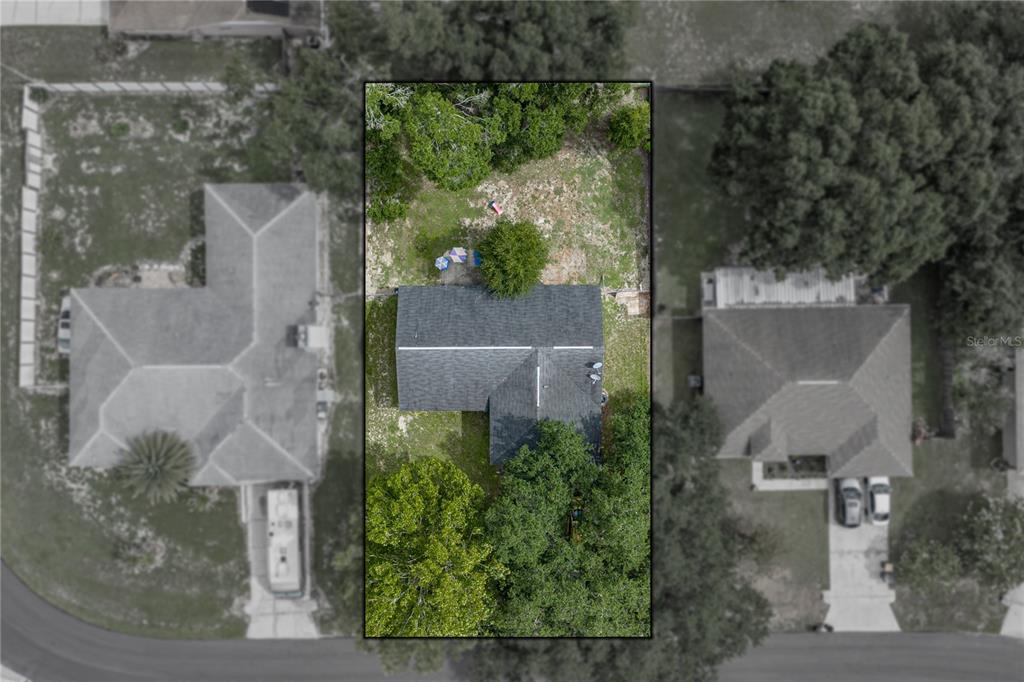 An aerial view shows a house with a dark roof surrounded by trees and grass — 8054 KAITLIN CIRCLE, LAKELAND, FL