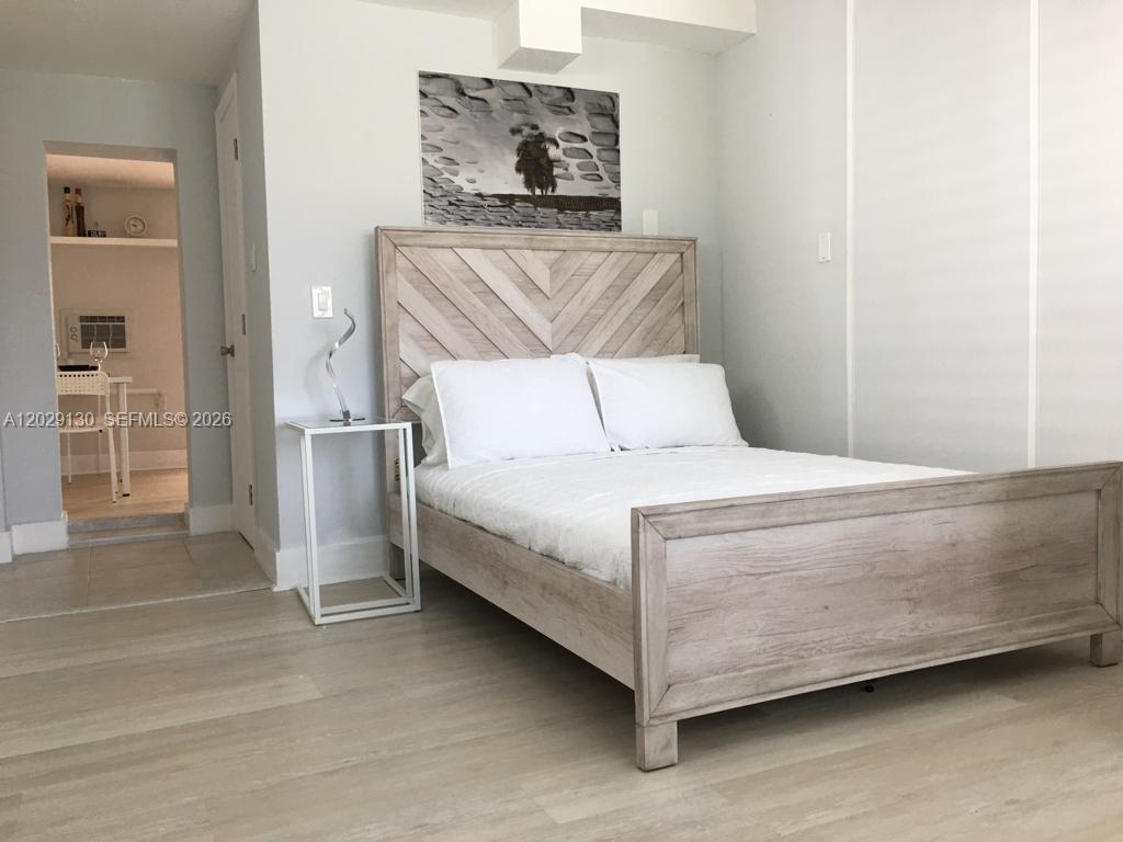 A bedroom features a light wood chevron-patterned headboard, white bedding, and a small metal side table — 7525 S Waterway Dr, Miami FL 33155, MIAMI, FL