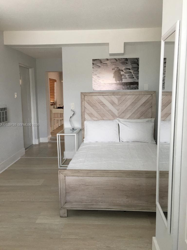 A bedroom features a light wood bed frame, white bedding, and a modern side table — 7525 S Waterway Dr, Miami FL 33155, MIAMI, FL