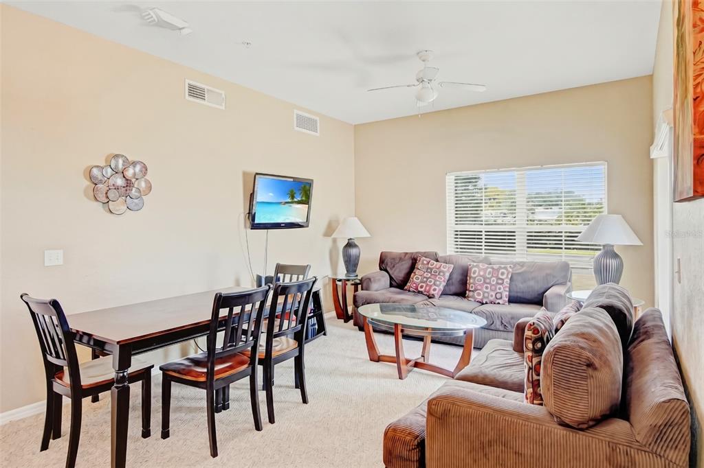 A living and dining area features brown sofas, a wooden table, and a wall-mounted television — 2610 LODI CIRCLE UNIT 107, KISSIMMEE, FL