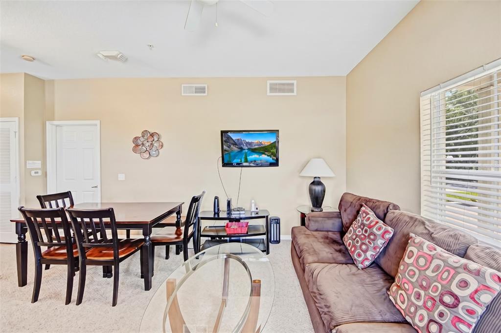 A living and dining room area features a brown sofa, a dining table, and a television — 2610 LODI CIRCLE UNIT 107, KISSIMMEE, FL