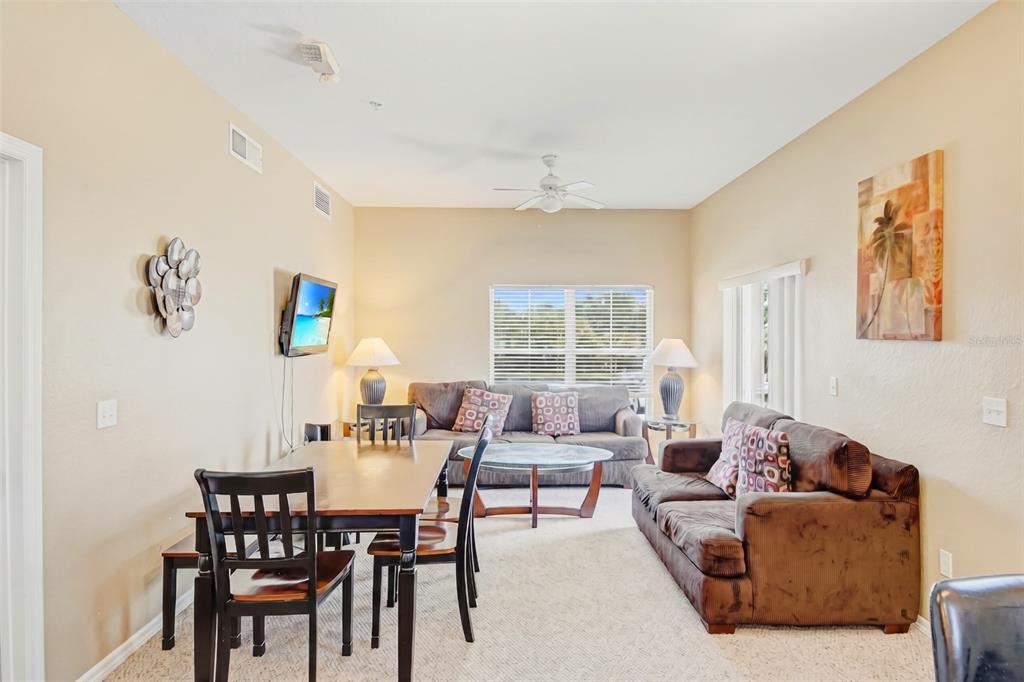 A living and dining room area features brown sofas, a wooden table, and carpeted floors — 2610 LODI CIRCLE UNIT 107, KISSIMMEE, FL