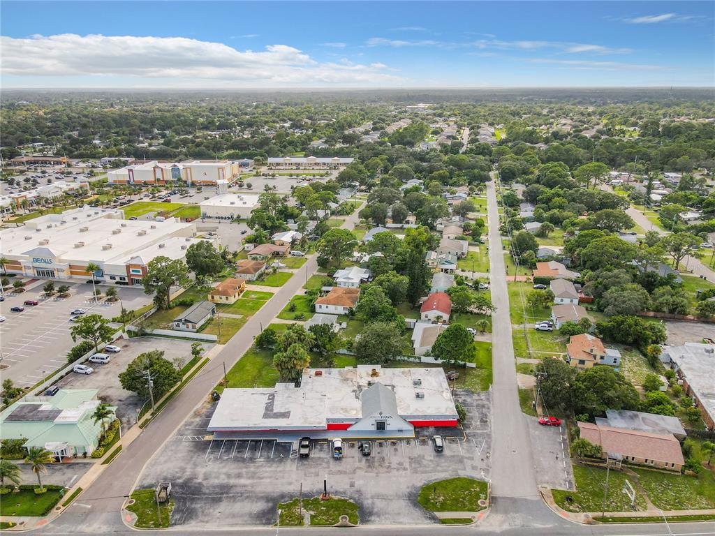 An aerial view shows a commercial building with a parking lot surrounded by residential houses — 2300 S WASHINGTON AVENUE, TITUSVILLE, FL