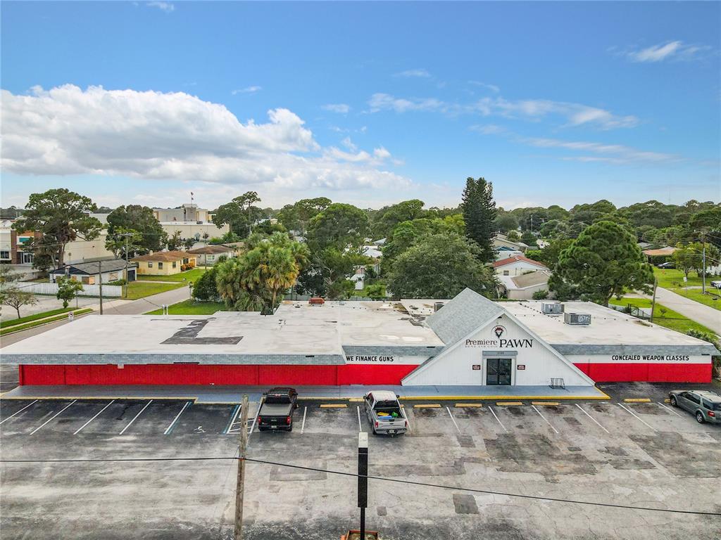 An aerial view shows a commercial building with a red base and parking lot — 2300 S WASHINGTON AVENUE, TITUSVILLE, FL