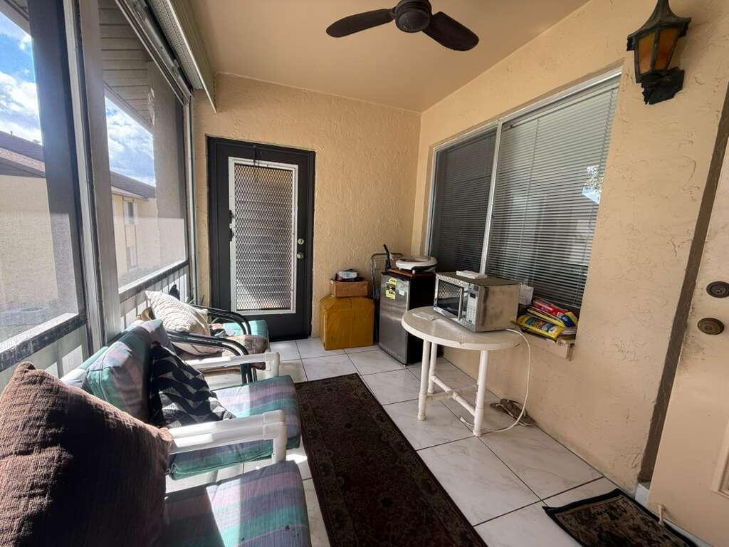 A screened-in porch features tile flooring, a ceiling fan, patio furniture, and a small kitchenette area — 213 Pine Hov Circle # D2, FL 33463, FL
