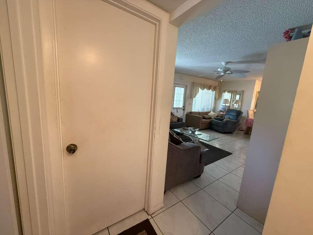A closed white door stands in the foreground, opening into a tiled living room area — 213 Pine Hov Circle # D2, FL 33463, FL