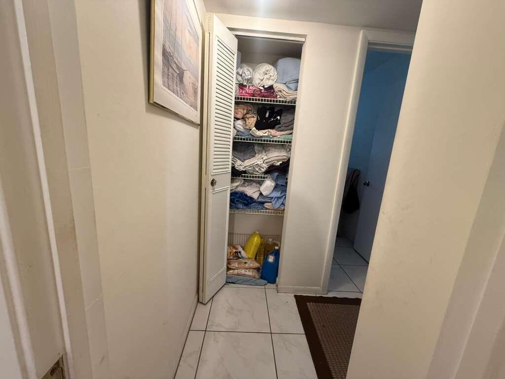 A hallway features a louvered-door linen closet with wire shelving and white tile flooring — 213 Pine Hov Circle # D2, FL 33463, FL