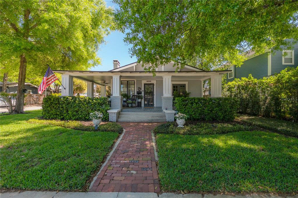 A single-story house with a brick walkway, front porch, and American flag — 6009 N SUWANEE AVENUE, TAMPA, FL