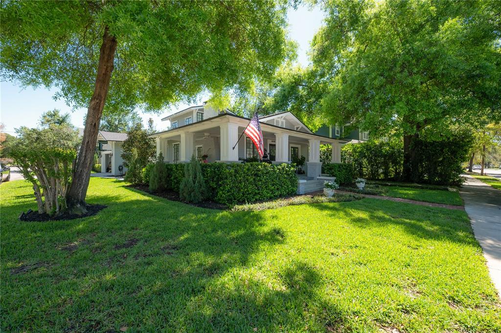 A single-story house with a front porch, American flag, and large trees in the yard — 6009 N SUWANEE AVENUE, TAMPA, FL