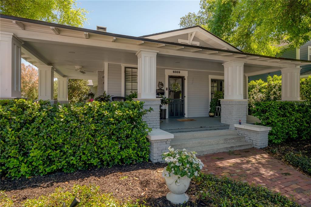 A gray bungalow features a wide front porch with white columns and brick bases — 6009 N SUWANEE AVENUE, TAMPA, FL