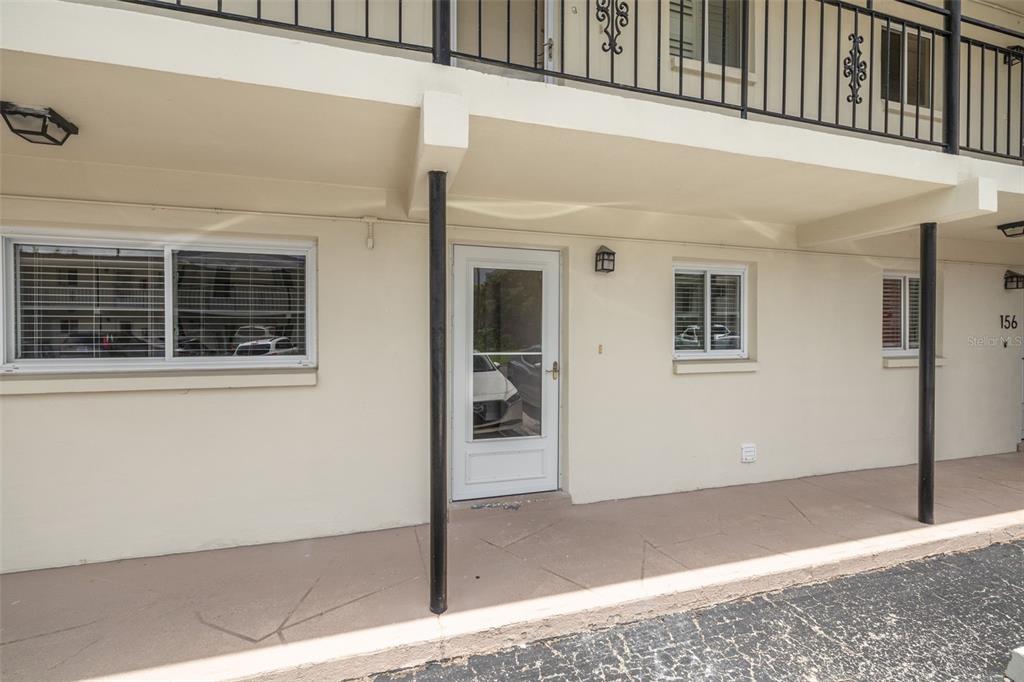 A ground-level apartment entrance features a white door, two windows, and a covered walkway — 4550 OVERLOOK DRIVE NE UNIT 155, ST PETERSBURG, FL