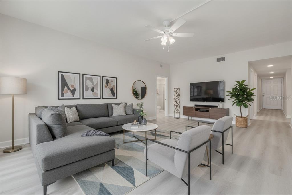 A modern living room features a gray sectional sofa, two armchairs, and a television console — 4550 OVERLOOK DRIVE NE UNIT 155, ST PETERSBURG, FL