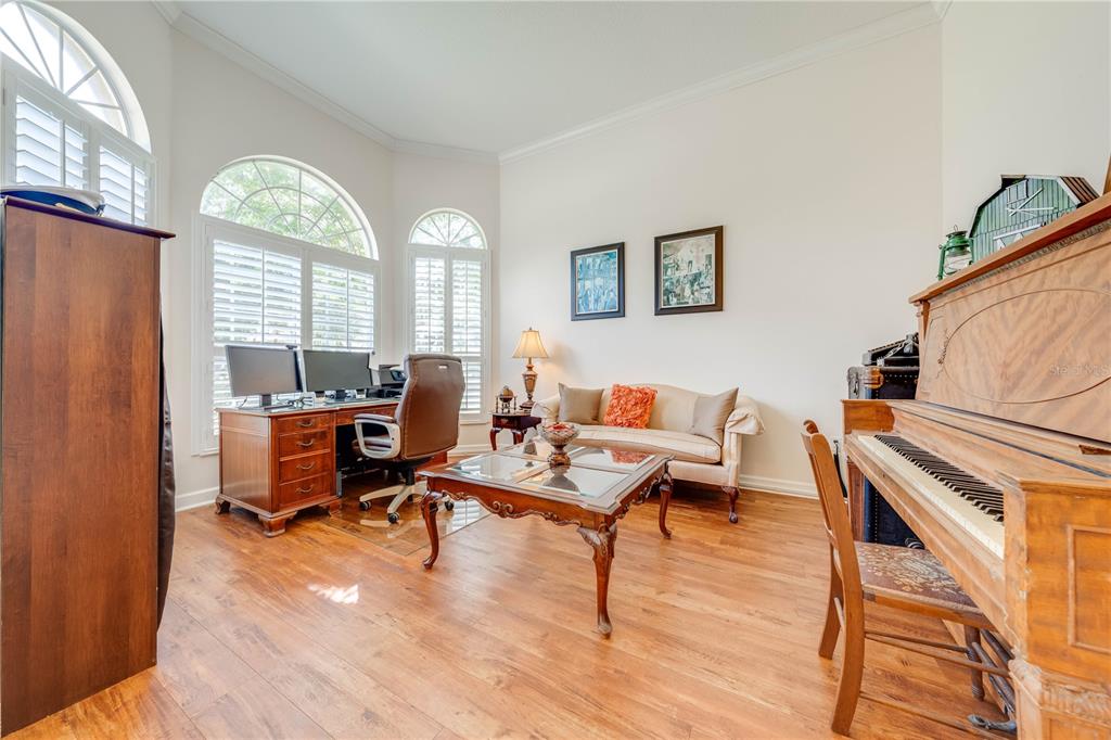 A home office featuring a desk, sofa, coffee table, and an upright piano on wood floors — 1648 MARINA LAKE DRIVE, KISSIMMEE, FL