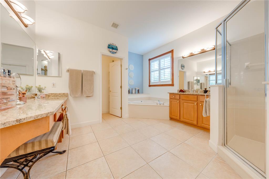 A bathroom features a soaking tub, a glass shower, and dual vanities with granite countertops — 1648 MARINA LAKE DRIVE, KISSIMMEE, FL