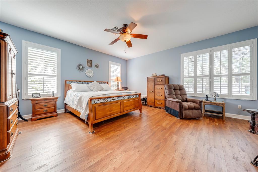 A bedroom features light blue walls, wood flooring, a wooden bed frame, and plantation shutters — 1648 MARINA LAKE DRIVE, KISSIMMEE, FL