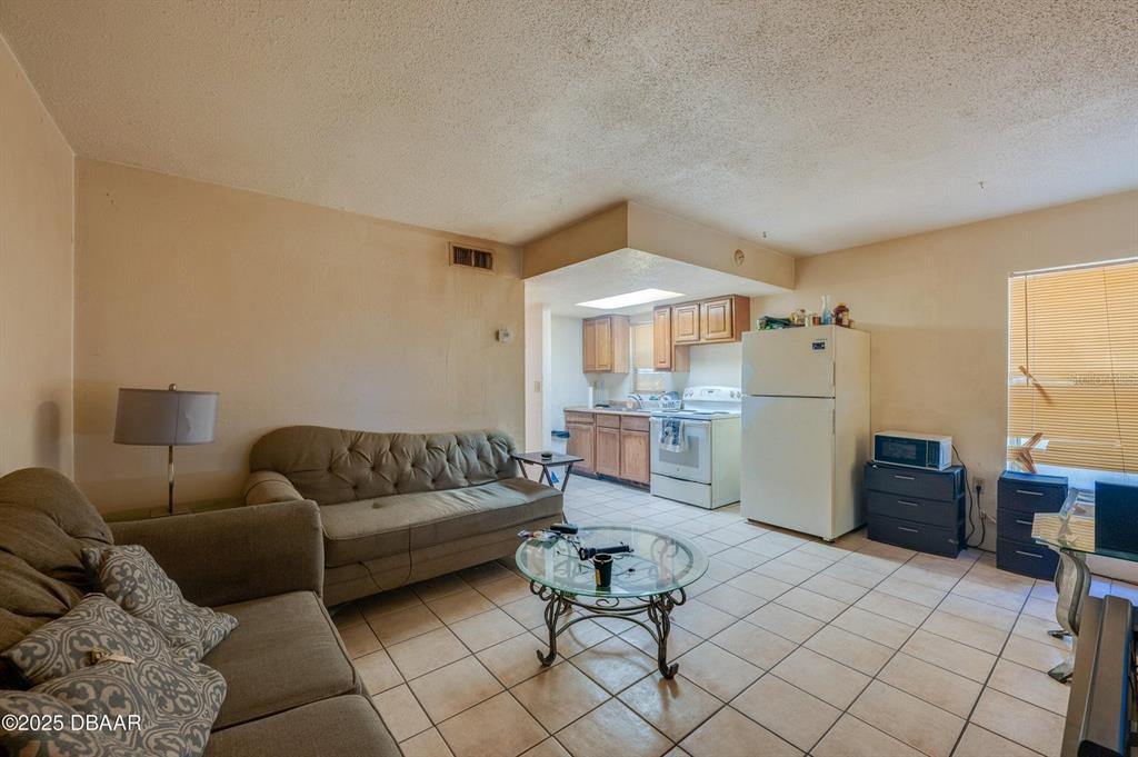 This living room features tile flooring and an open layout connected to the kitchen — 600 S SEGRAVE STREET, DAYTONA BEACH, FL