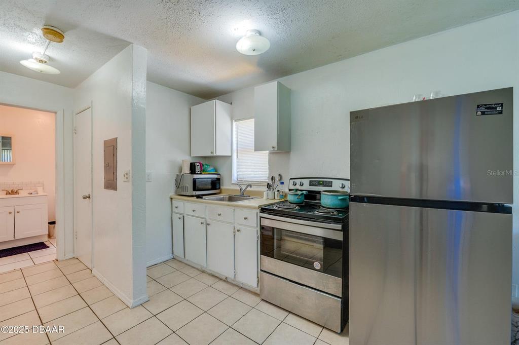 A kitchen features white cabinets, stainless steel appliances, and light-colored tile flooring — 600 S SEGRAVE STREET, DAYTONA BEACH, FL