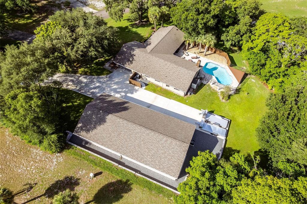 An aerial view shows a house with a swimming pool and a large detached garage — 1930 LONG POND DRIVE, LONGWOOD, FL