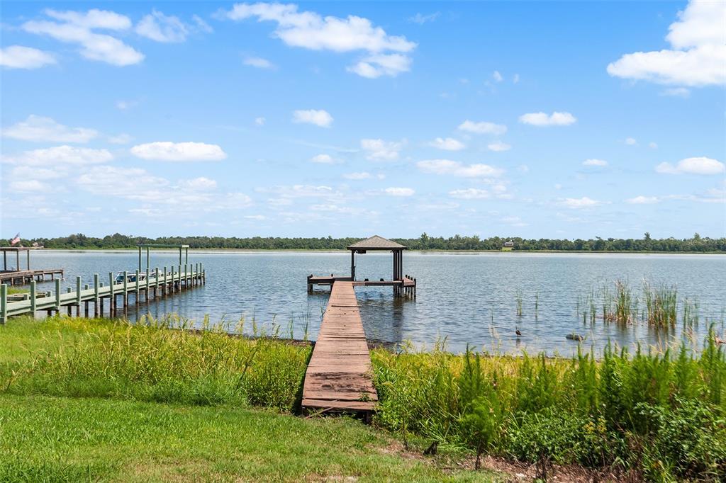 A wooden dock with a covered boat slip extends into a large lake — 4123 ISLAND LAKES DRIVE, WINTER HAVEN, FL