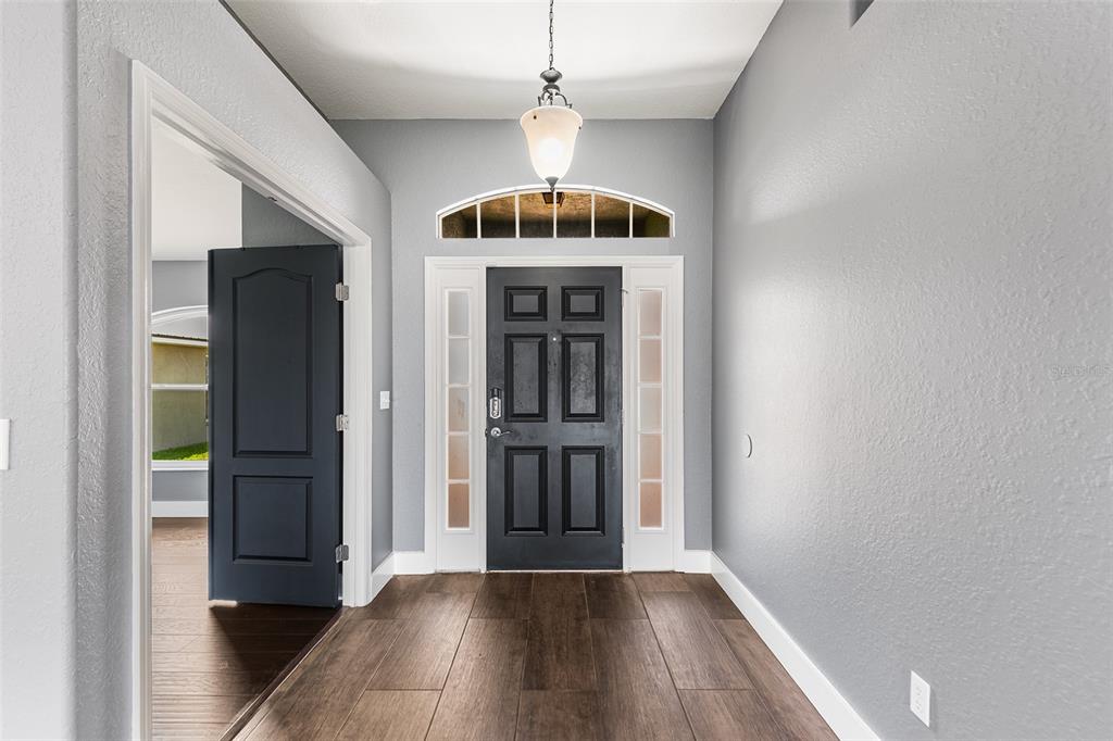 An entryway features a dark front door, light gray walls, and wood-look tile flooring — 4123 ISLAND LAKES DRIVE, WINTER HAVEN, FL