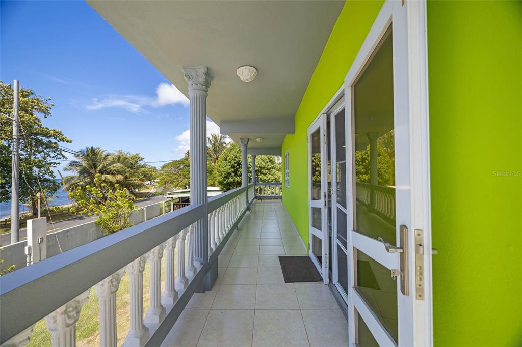 A bright green exterior balcony features white railings, classical columns, and a tiled floor — CARR. 3 BO. GUARDARRAYA SECTOR COOPERATIVO UNIT KM 113.3, PATILLAS, PR