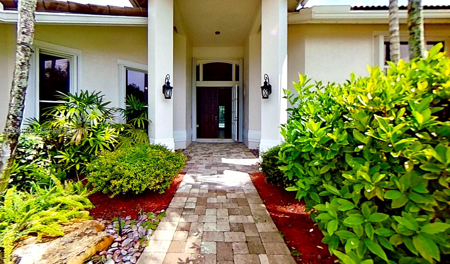 A stone walkway leads to the front entrance of a house with lush landscaping — 405 Sabal Way, Weston FL 33326, WESTON, FL