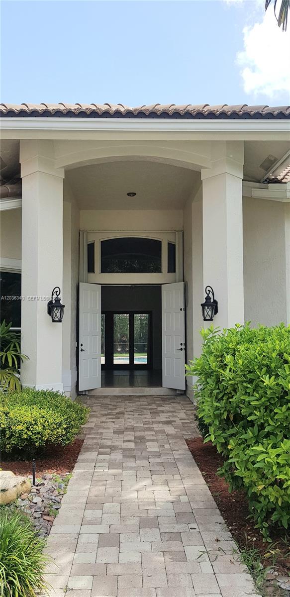 A stone walkway leads to an open double-door entrance of a house with white columns — 405 Sabal Way, Weston FL 33326, WESTON, FL