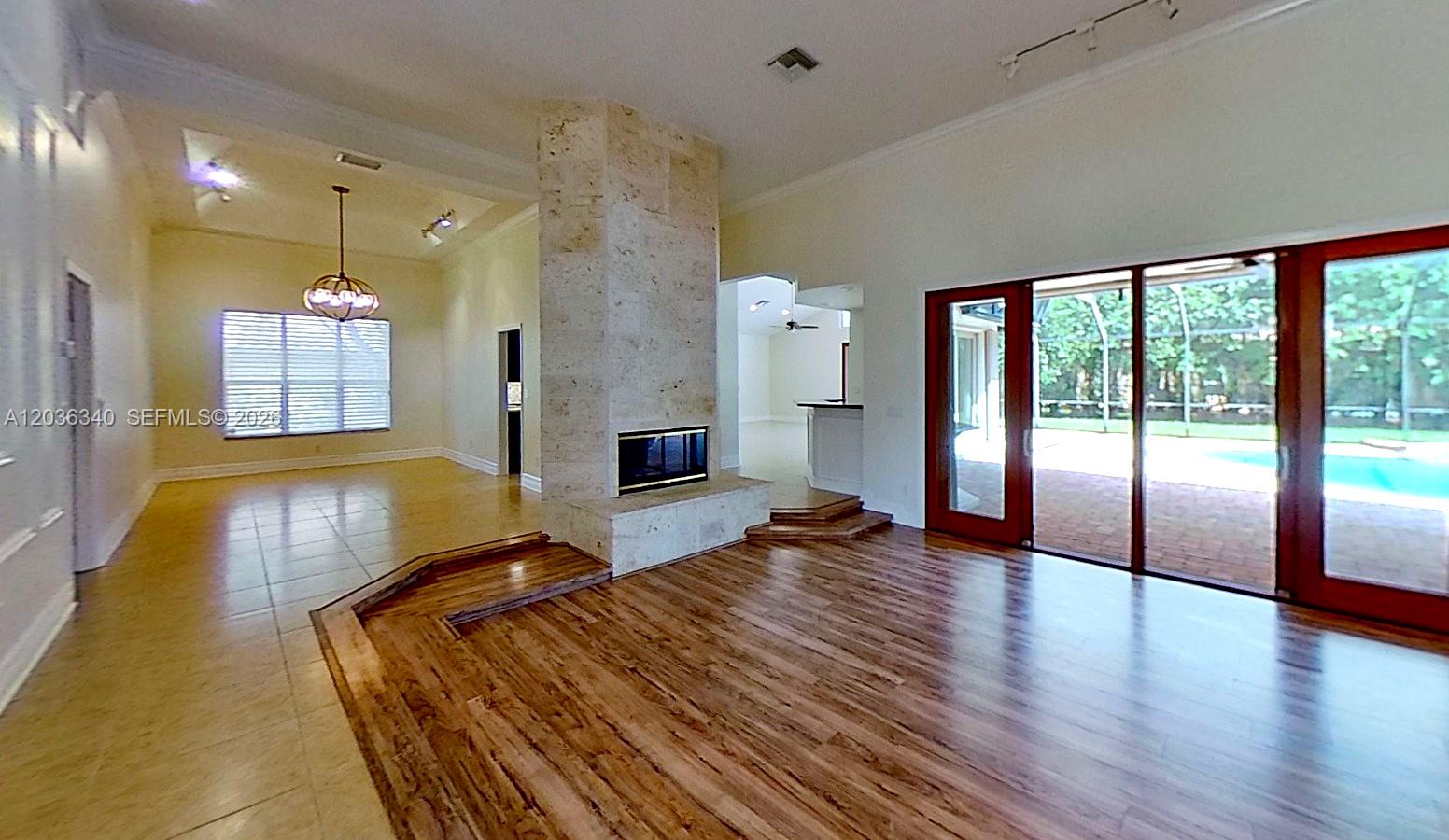A living room features a stone fireplace, wood flooring, and sliding glass doors to a pool — 405 Sabal Way, Weston FL 33326, WESTON, FL