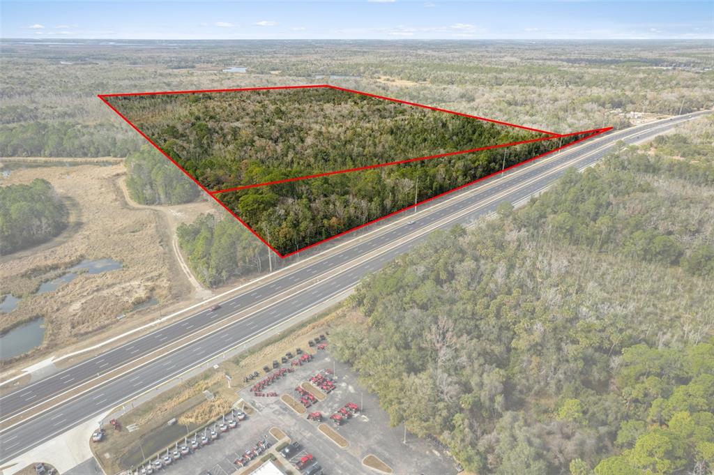 An aerial view shows a wooded plot of land outlined in red beside a highway — 2872 S SUNCOAST BOULEVARD, HOMOSASSA, FL