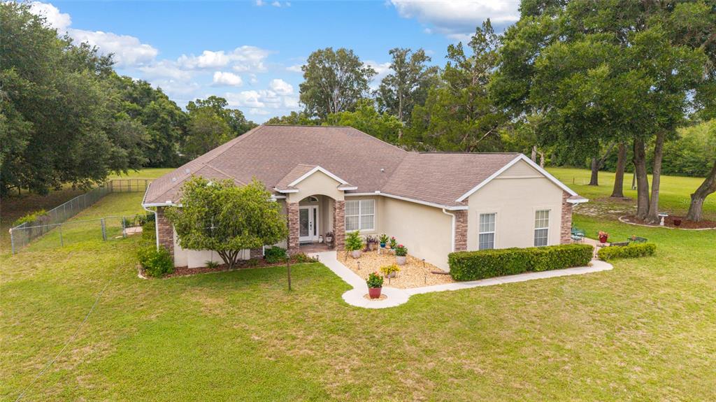 An exterior view of a single-story beige house with a brown roof and stone accents — 435 NE 155TH STREET ROAD, CITRA, FL