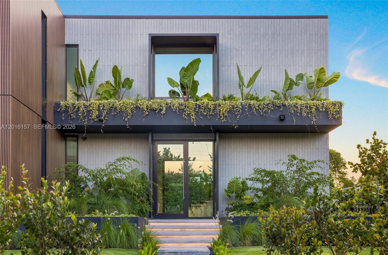 A modern two-story house exterior features vertical gray siding, a glass entryway, and integrated planters — 4550 N Jefferson Ave, Miami Beach FL 33140, MIAMI BEACH, FL