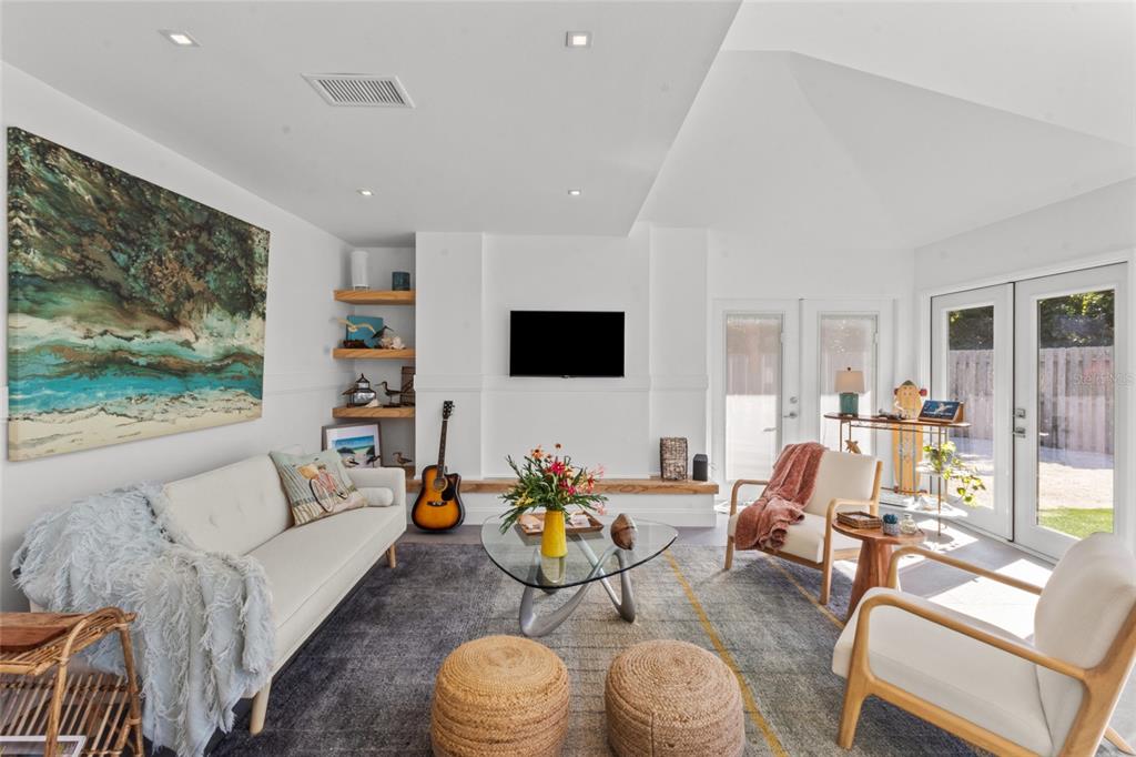 A bright living room features a white sofa, two armchairs, a glass coffee table, and a television — 624 SAINT JUDES DRIVE, LONGBOAT KEY, FL