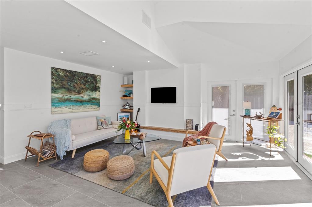 A bright living room features a white sofa, two armchairs, a glass coffee table, and tile flooring — 624 SAINT JUDES DRIVE, LONGBOAT KEY, FL