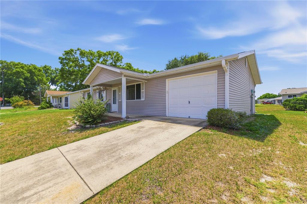 A single-story house with light gray vinyl siding, a front porch, and a one-car garage — 10986 SW 83RD AVENUE, OCALA, FL