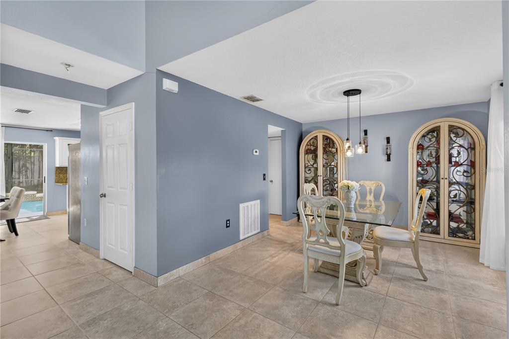 A dining area features a glass table, ornate chairs, arched display cabinets, and tile flooring — 4912 NEWTON COURT, ST CLOUD, FL