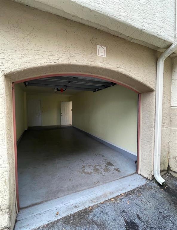An open garage with a concrete floor, two interior doors, and a letter H sign — 827 CAMARGO WAY UNIT 112, ALTAMONTE SPRINGS, FL