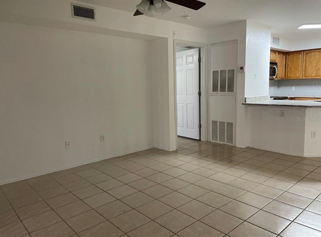 An interior view shows a tiled living area with a ceiling fan and kitchen pass-through — 827 CAMARGO WAY UNIT 112, ALTAMONTE SPRINGS, FL