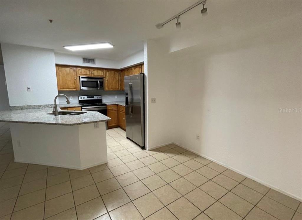 A kitchen with wood cabinets, stainless steel appliances, and a granite-topped breakfast bar — 827 CAMARGO WAY UNIT 112, ALTAMONTE SPRINGS, FL