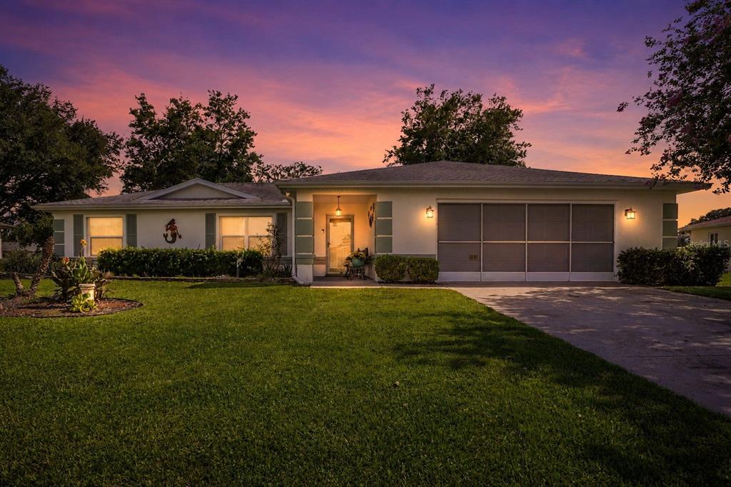 A single-story house with a screened garage and a front lawn at sunset — 6169 SW 100TH LOOP, OCALA, FL