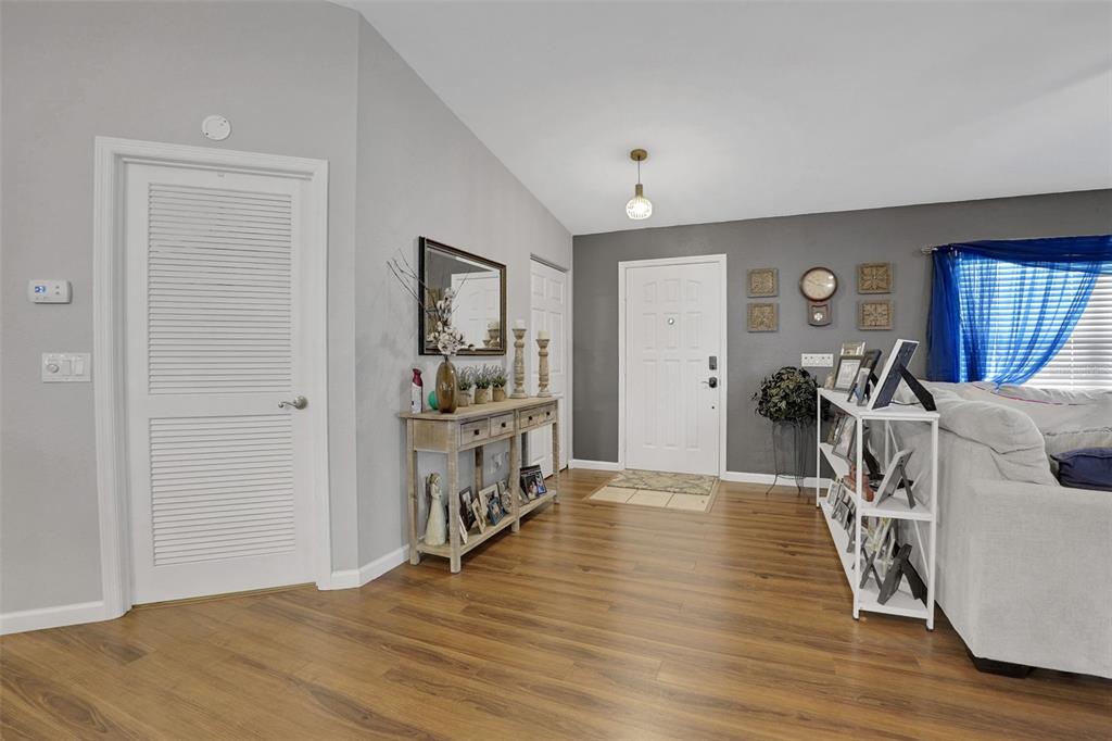 A living room entryway features wood-look flooring, a white front door, and a console table — 6169 SW 100TH LOOP, OCALA, FL