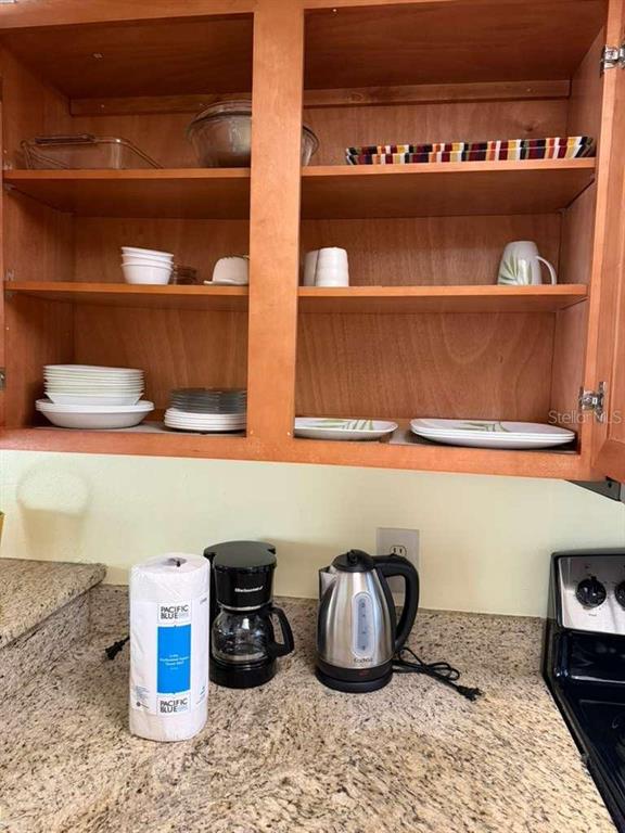 A kitchen cabinet with open shelving sits above a countertop with a coffee maker and kettle — 3197 SEA WORLD COURT, KISSIMMEE, FL