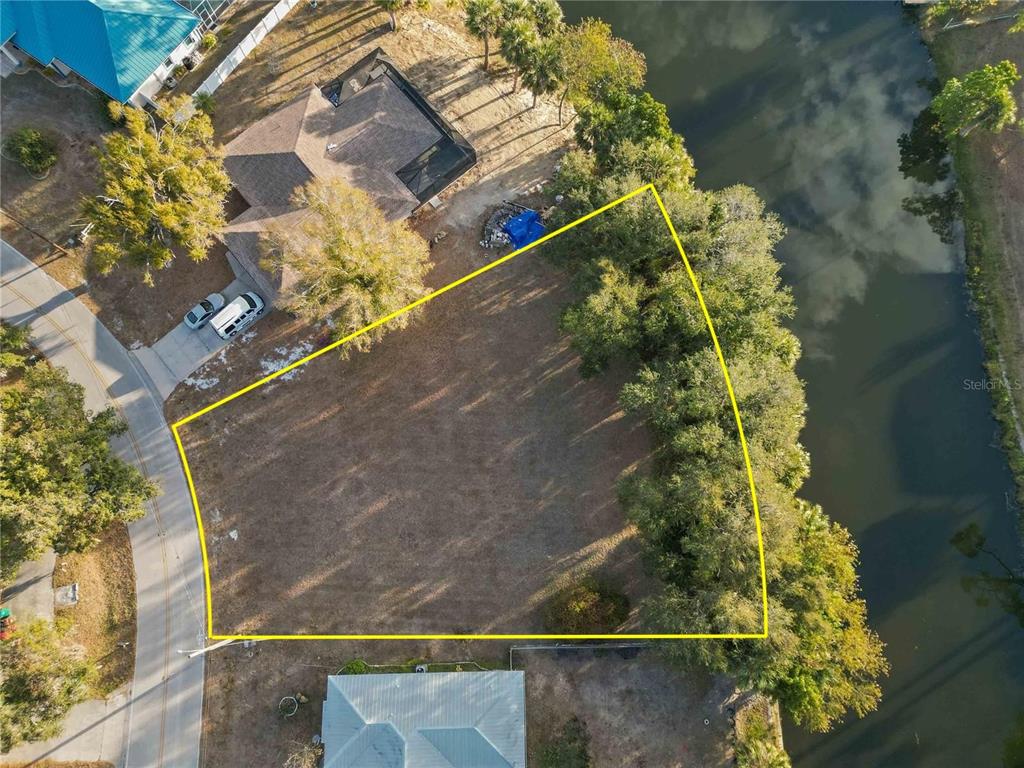 An aerial view shows a vacant, trapezoidal lot situated between a road and a canal — 20551 ALBURY DRIVE, PORT CHARLOTTE, FL