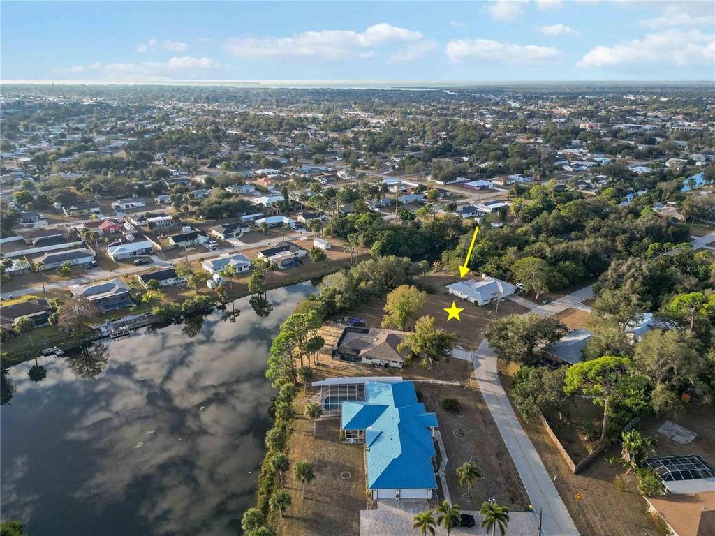 An aerial view shows a residential neighborhood with a canal and a marked house — 20551 ALBURY DRIVE, PORT CHARLOTTE, FL
