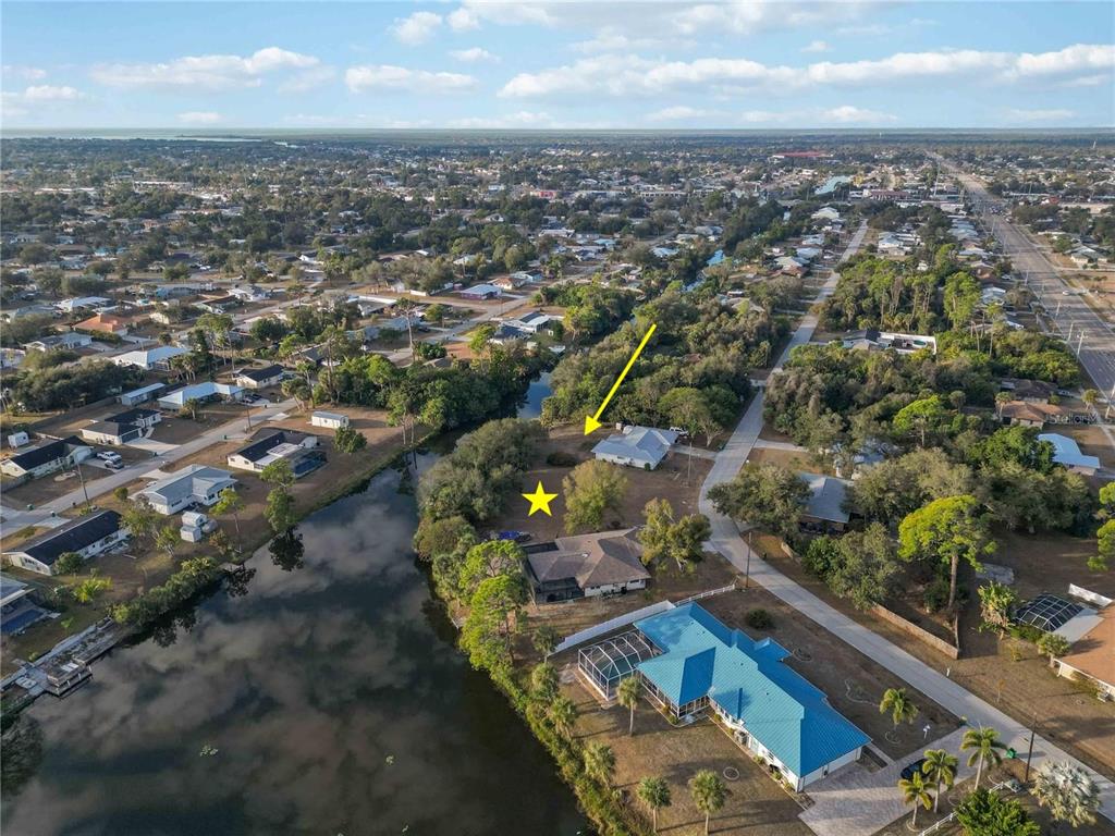 An aerial view shows a residential lot with a yellow star and arrow near water — 20551 ALBURY DRIVE, PORT CHARLOTTE, FL