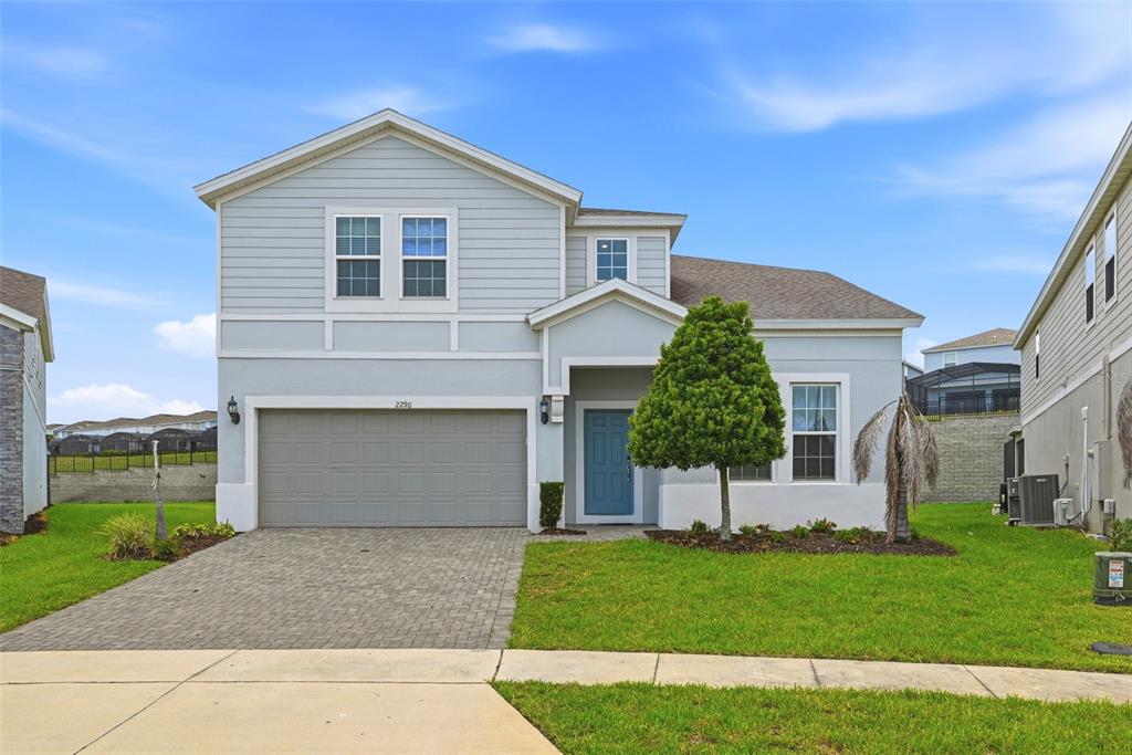 A two-story house with light blue siding, a gray garage door, and a blue front door — 2290 LELANI CIRCLE, DAVENPORT, FL