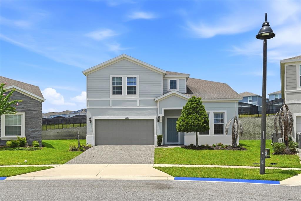 A two-story house with light gray siding, a two-car garage, and a paved driveway — 2290 LELANI CIRCLE, DAVENPORT, FL