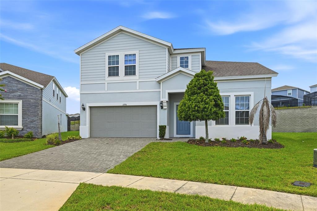 A two-story house with light blue siding, a gray garage door, and a paved driveway — 2290 LELANI CIRCLE, DAVENPORT, FL