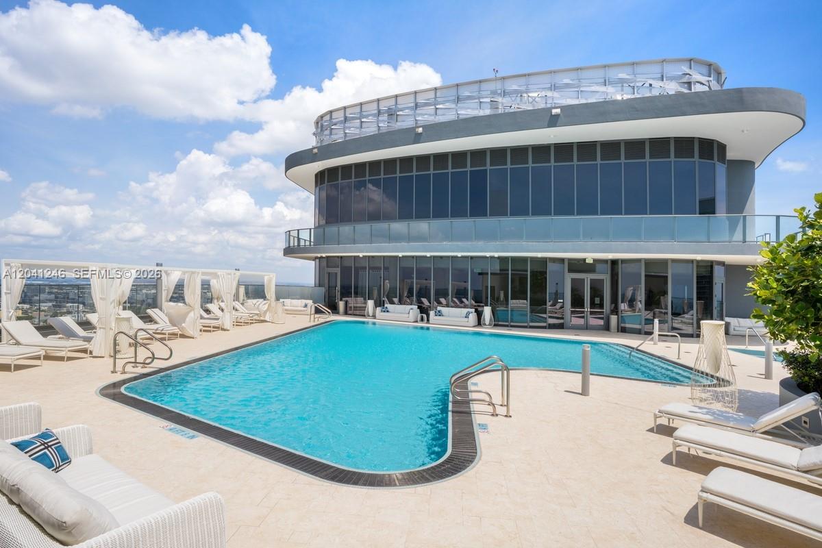 A rooftop swimming pool with lounge chairs and cabanas sits outside a modern glass building — 1000 Brickell Plz # 2101, Miami FL 33131, MIAMI, FL